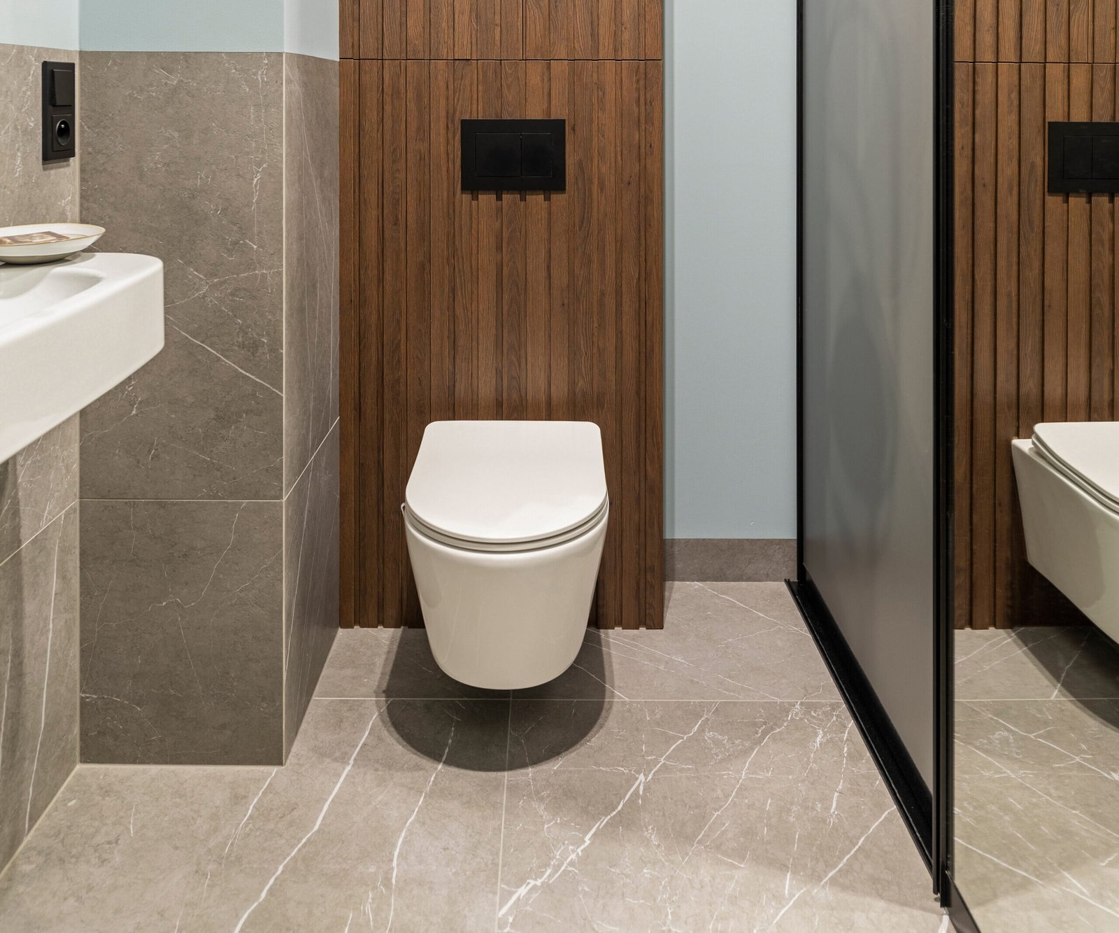 modern bright bathroom with white toilet seat wooden lamela wall mirror grey wall scaled e1776533085973