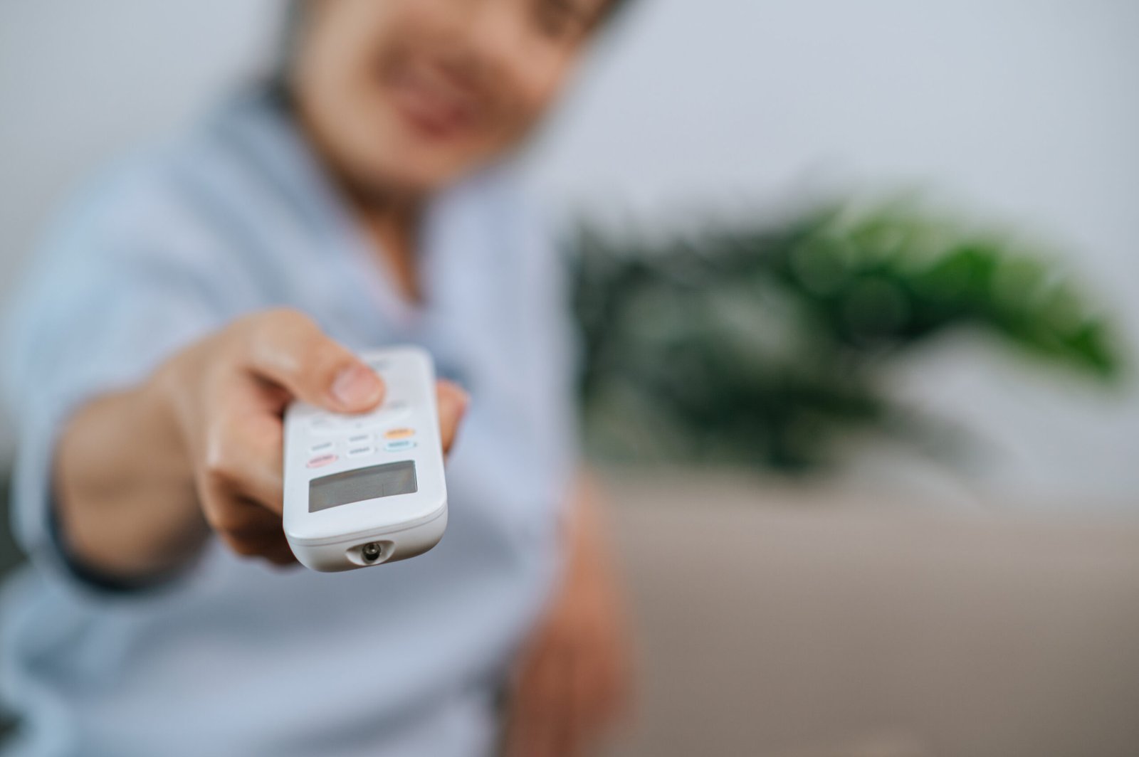 close up selective focus hand woman holding use remote control open aircondition living room home scaled